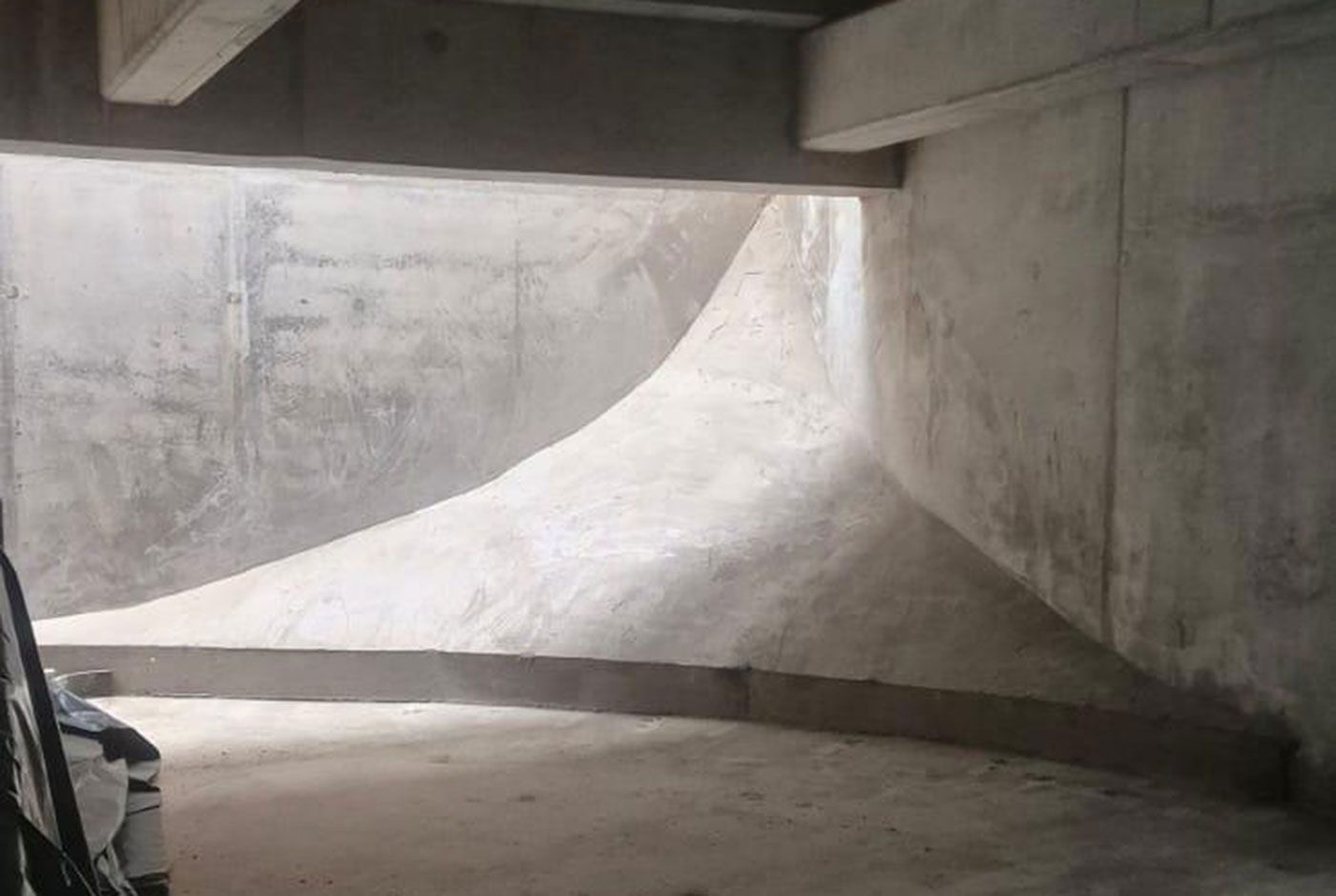 Concrete building structure with curved sloping floor, walls and ceiling.