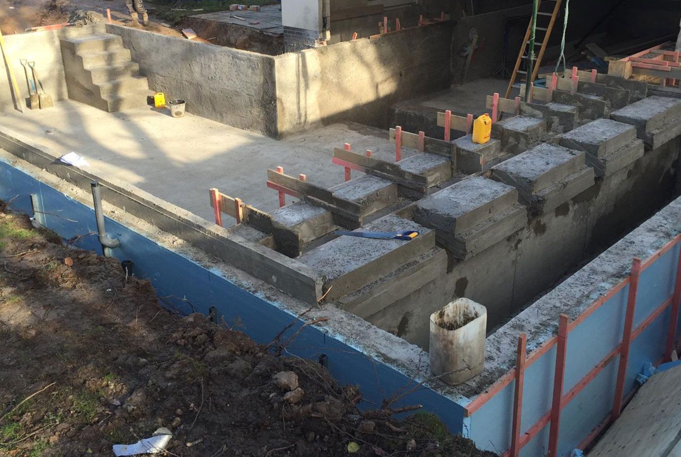 Construction site for a deck-level pool, with concrete shell, rebar and blue surround to reinforce.