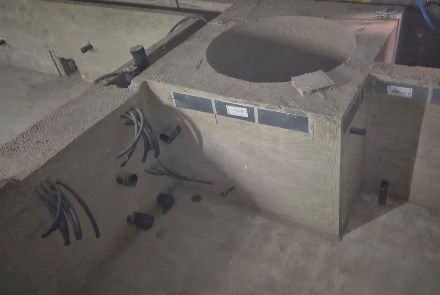 The concrete shell of a deck-level pool with plunge pool feature and multiple loose pipes and cables visible.