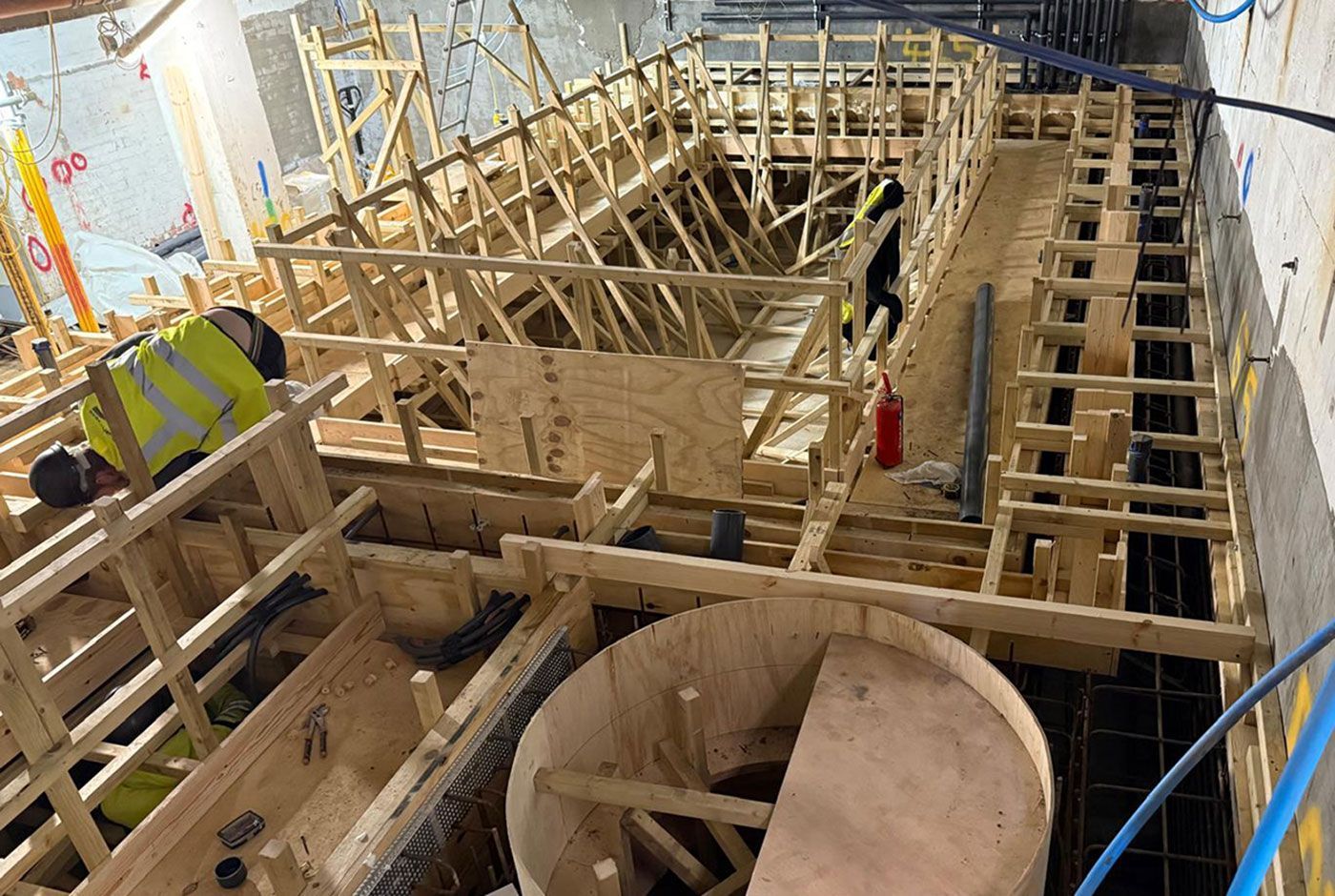 Wooden construction framework and circular formwork under construction for a deck-level pool.