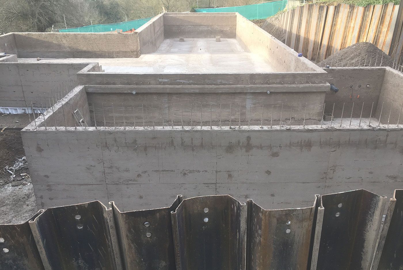The concrete shell of an infinity pool under construction, with wood formwork and rebar.