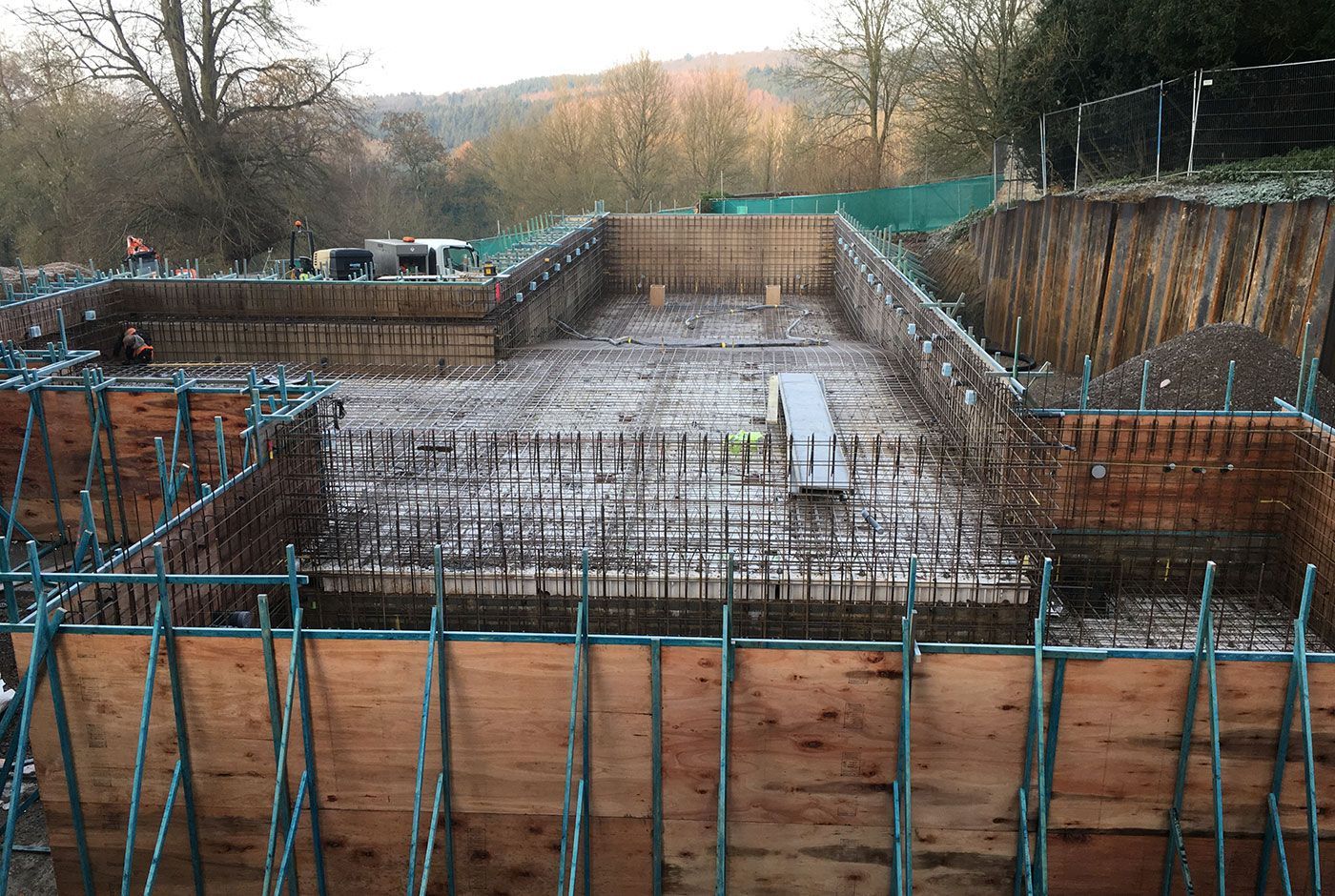 The foundation site of an infinity pool with steel rebar and wooden formwork, constructed within a residential garden.