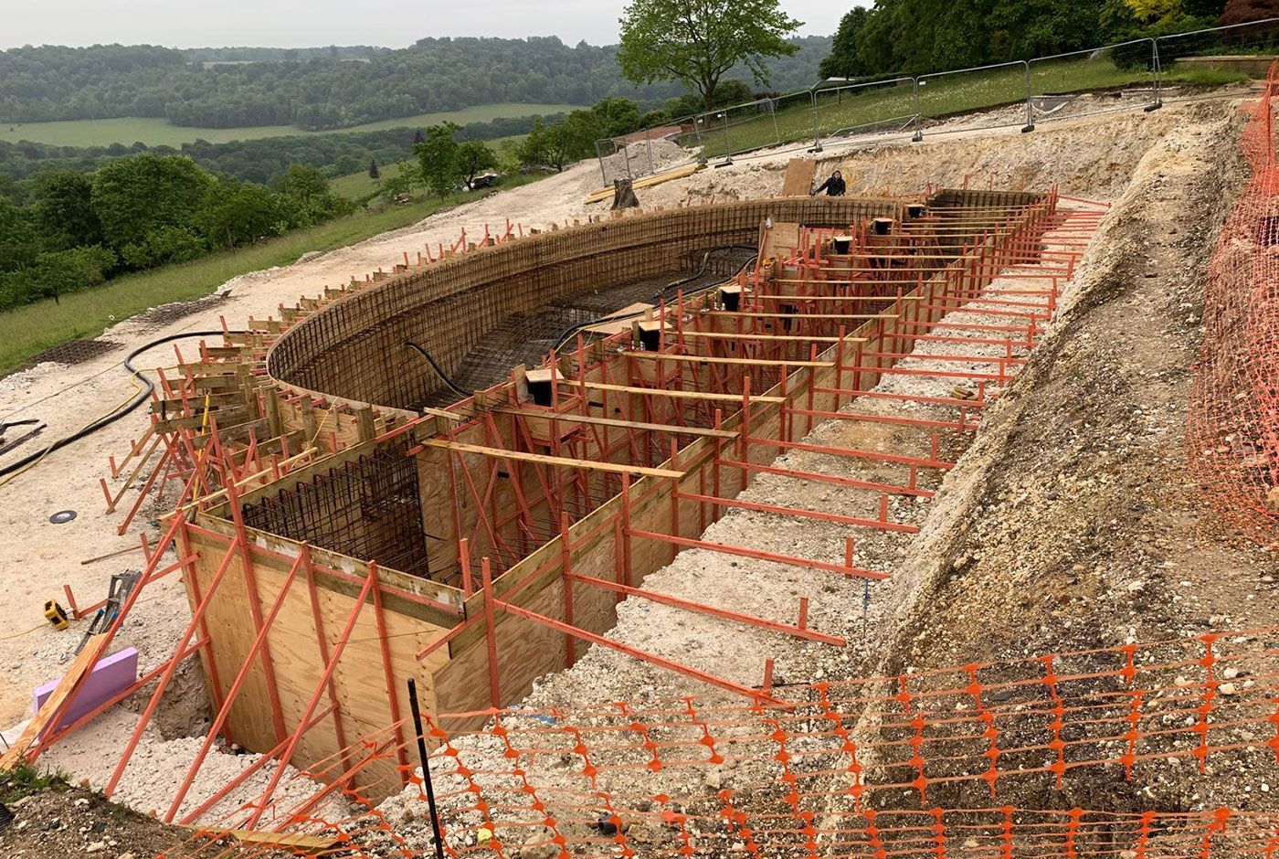 Excavation site for an infinity pool with wooden foundation forms and rebar on a hillside location.