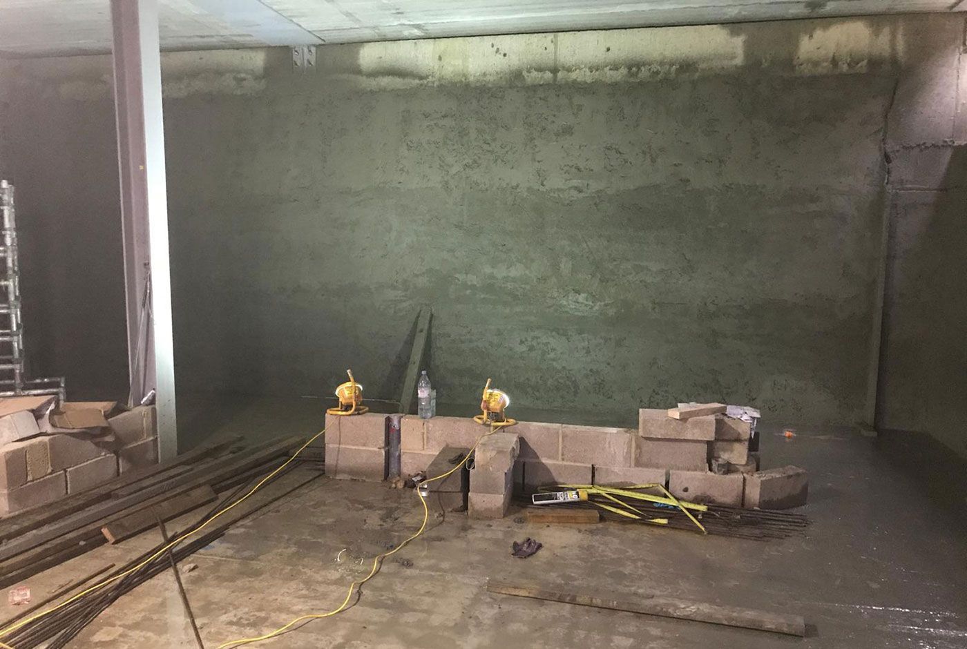 Pile-faced wall on a construction site with stacked concrete blocks and tools in a dim, unfinished room.