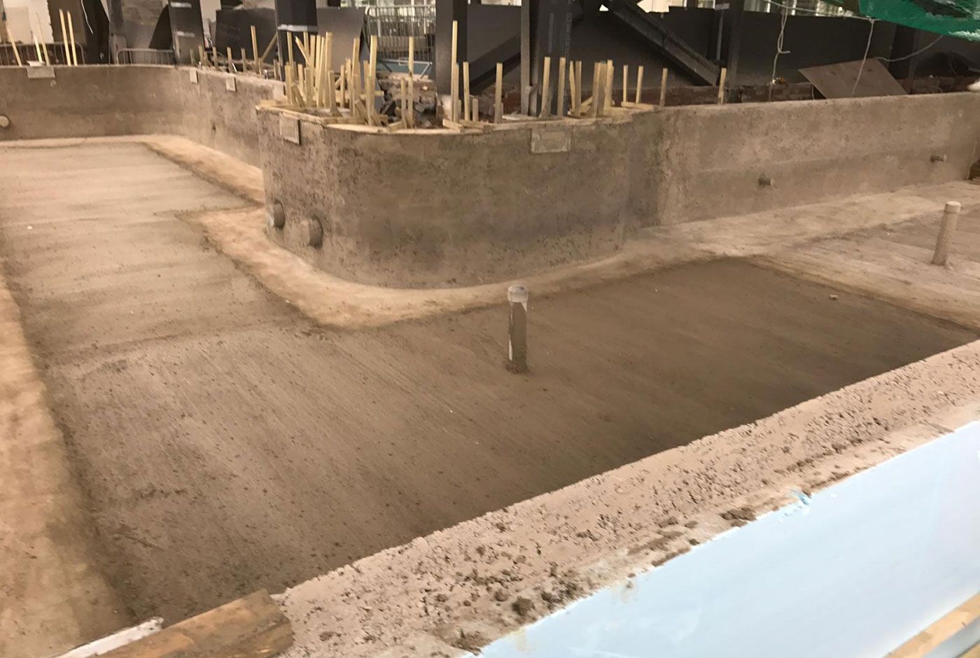 Skimmer pool under construction, with concrete walls with exposed rebar, the concrete base has just been sprayed.