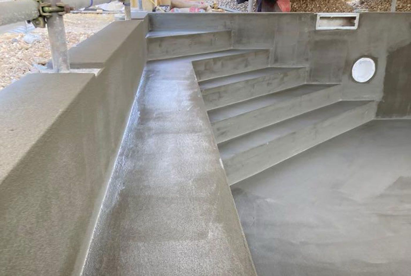 Detail of a completed concrete pool shell showing how steps and seating have been formed with concrete.