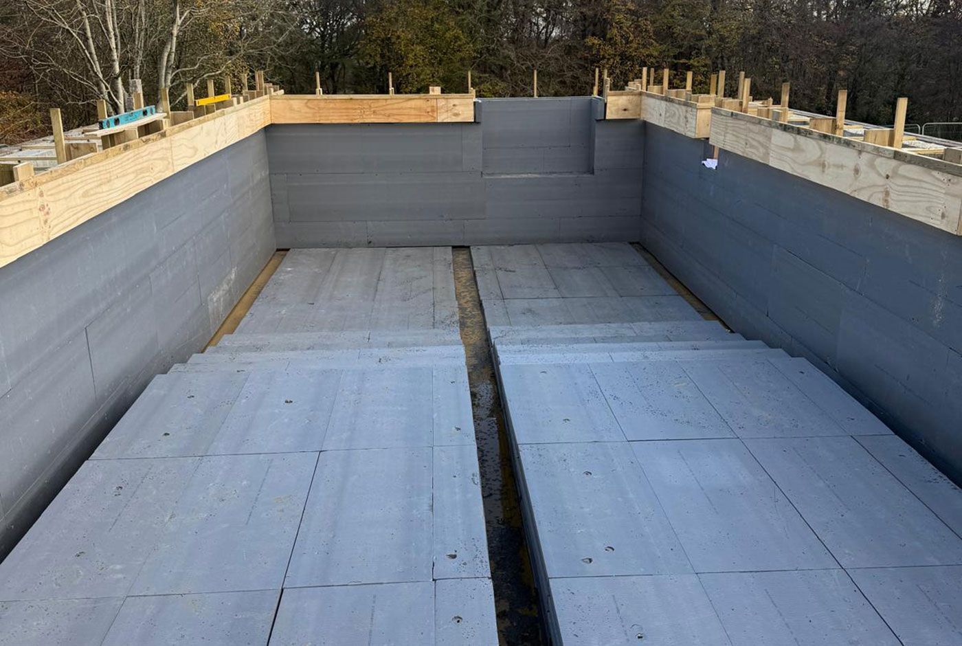 Empty concrete swimming pool under construction with gray walls and floor, viewed from one end