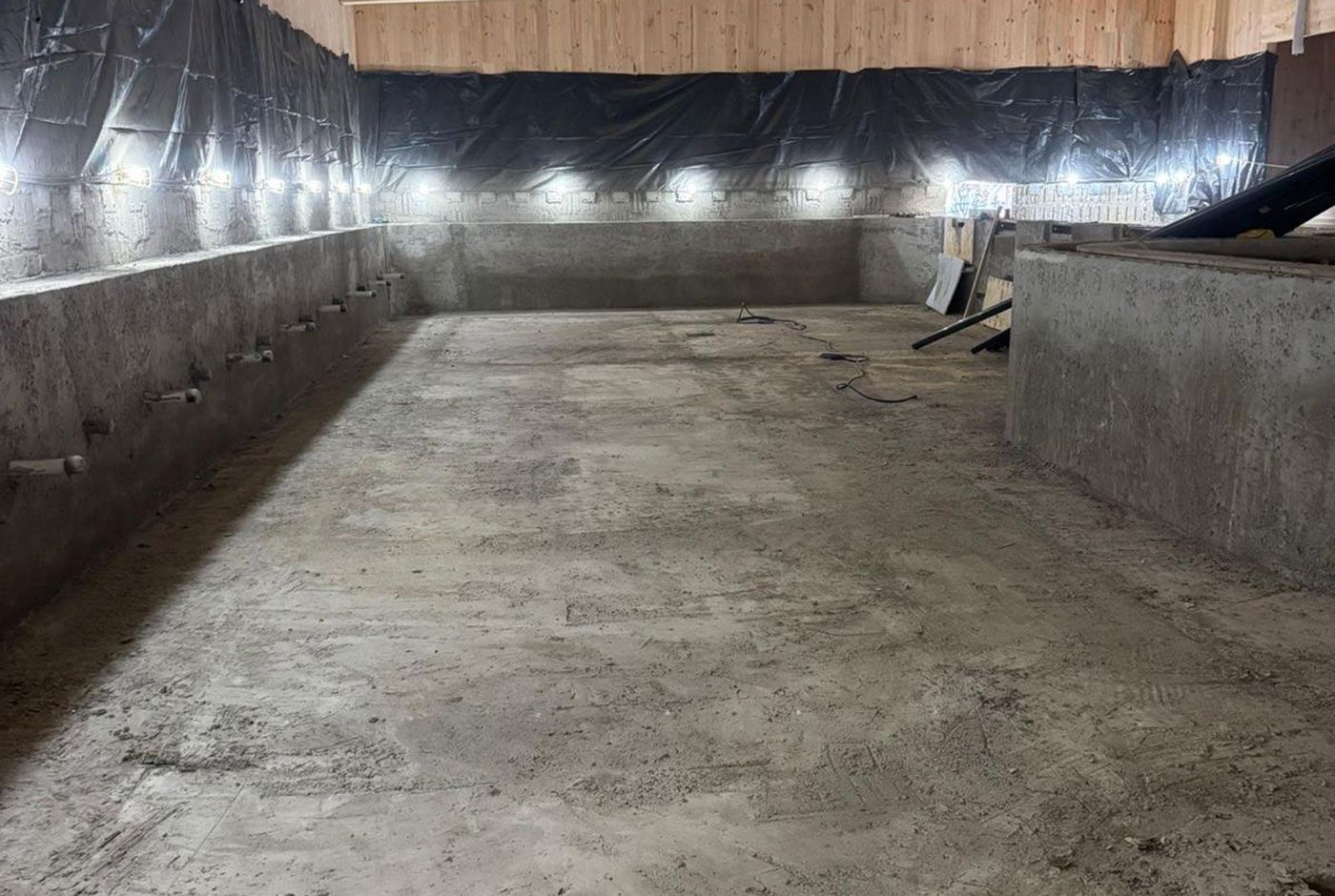 Indoor skimmer pool shell with unfinished walls and floor, panelled walls protected with black polythene.