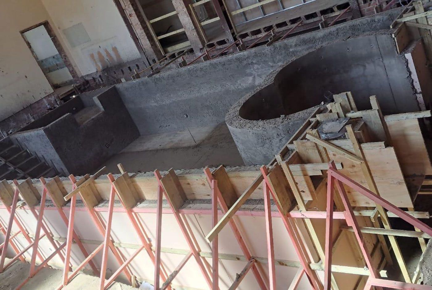Construction of an indoor spa/plunge pool in progress, concrete shell, wooden formwork supported by wooden struts. 