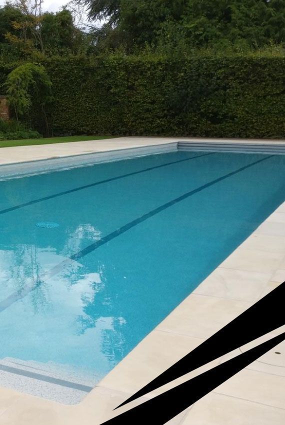 Outdoor swimming pool with clear blue water, large white umbrella and seating, surrounded by wall and greenery.