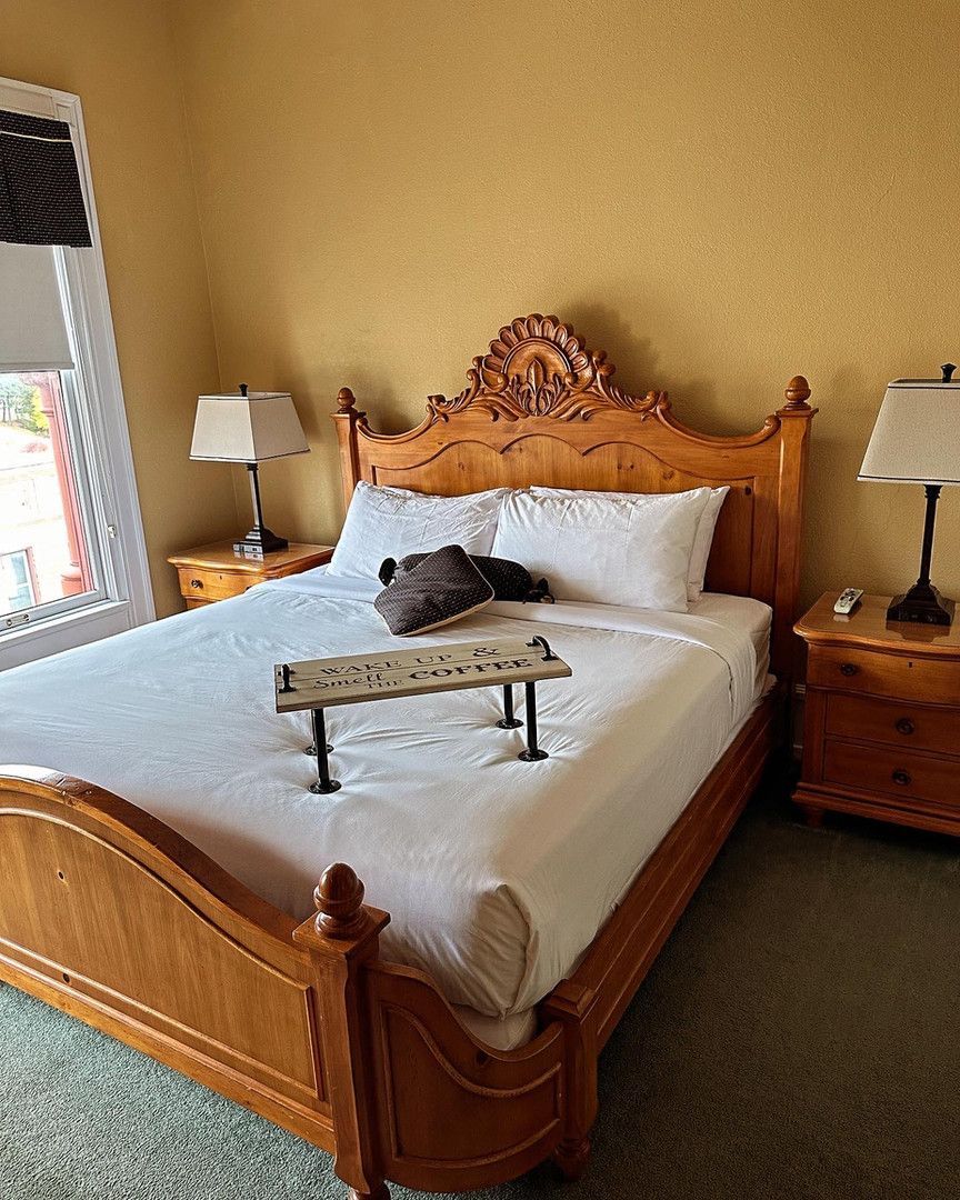 A bedroom with a bed , nightstands , lamps and a window.