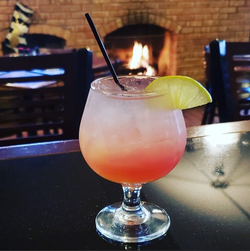 A drink with a straw and a slice of lime in front of a fireplace