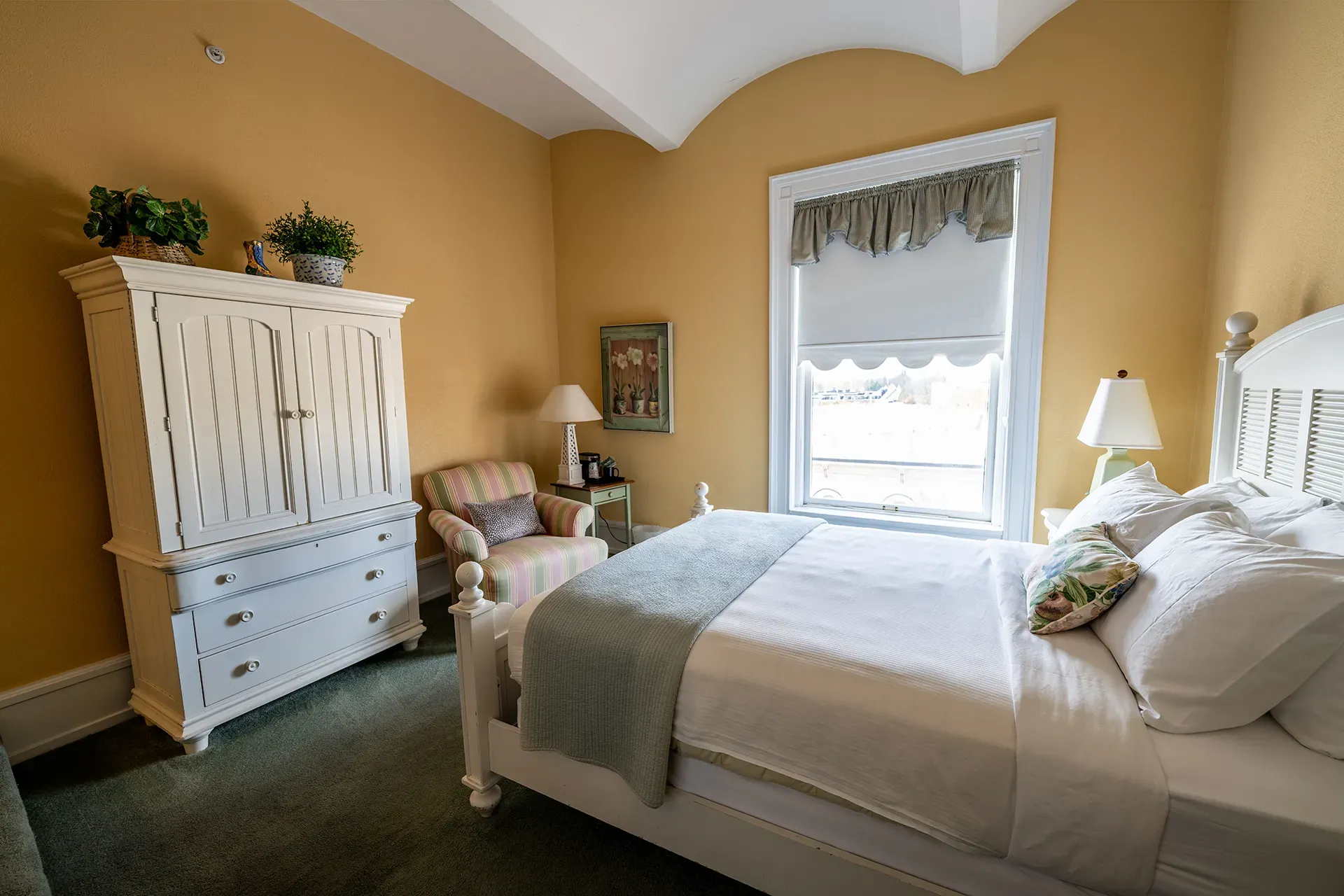 A bedroom with a bed , dresser , chair and window.