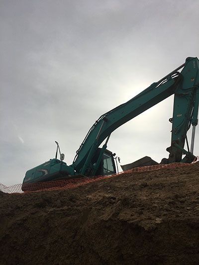 A large excavator is sitting on top of a pile of dirt.