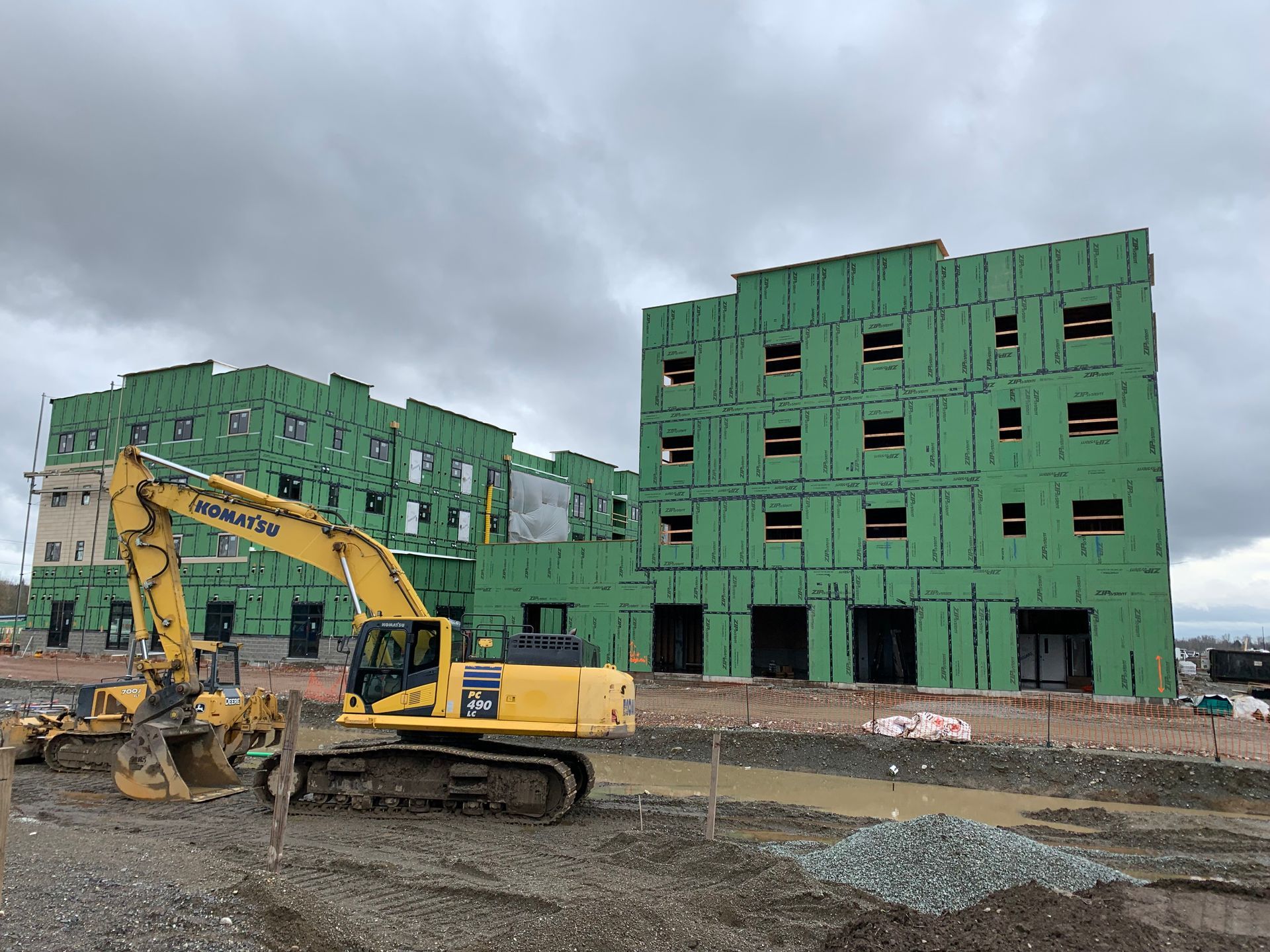 A large yellow excavator is parked in front of a building under construction.