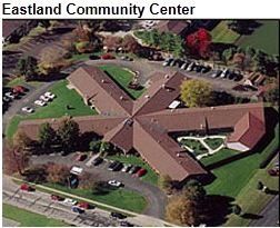 Aerial view of Eastland Community Center, a brown-roofed building in an X shape, surrounded by green lawns and parking lots.