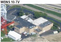 Aerial view of WBNS 10-TV building with a tall broadcast tower on the left and highway in the background.
