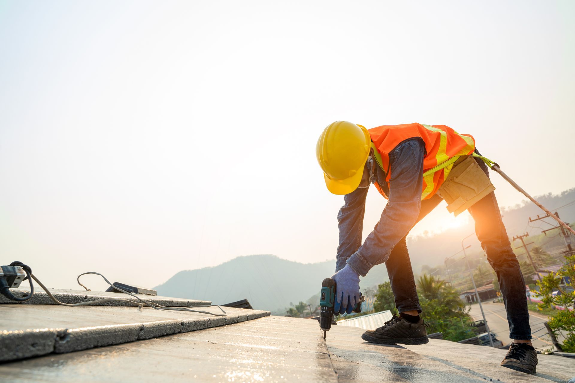 A man in a safety vest and hard hat is working on a roof, focusing on commercial roofing services. A man in a safety vest and hard hat is working on a roof, focusing on commercial roofing services.