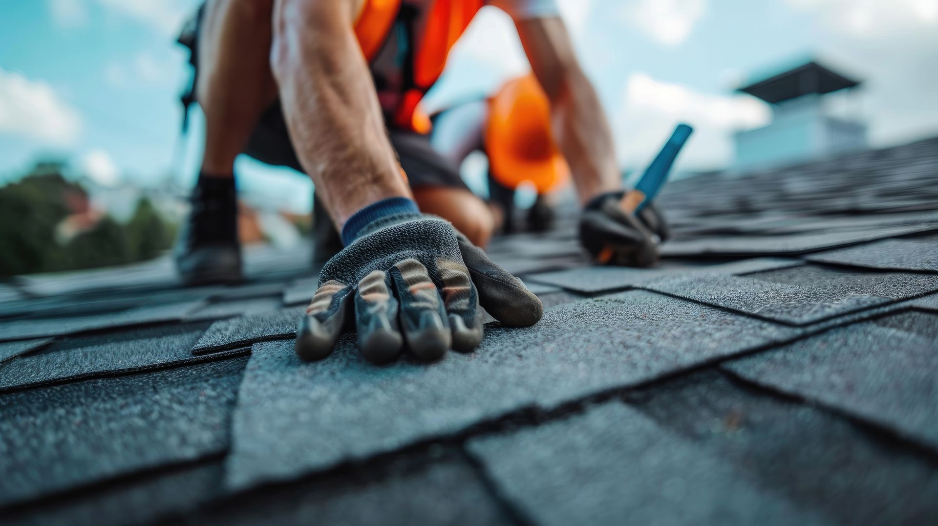 A roofer working in special protective workwear and gloves, repairing asphalt shingle roofing.