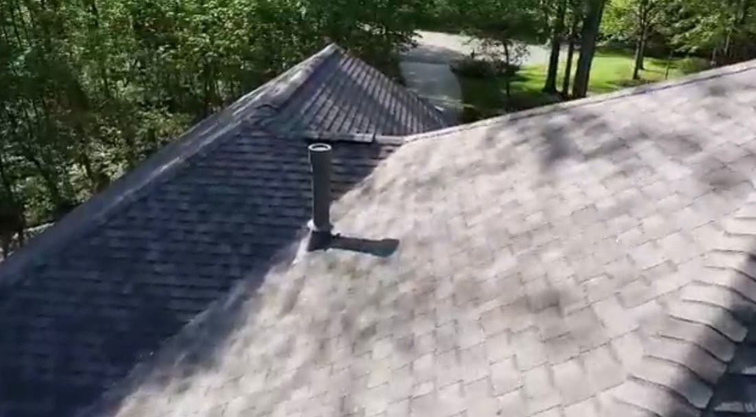 Gray asphalt shingle roof with a chimney. Trees in the background.