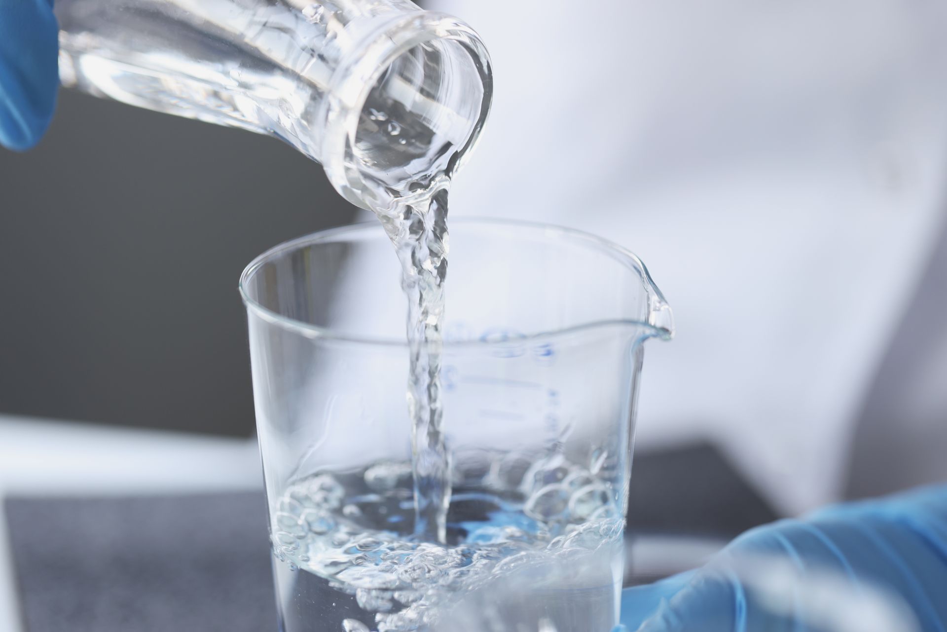A person is pouring liquid into a beaker.
