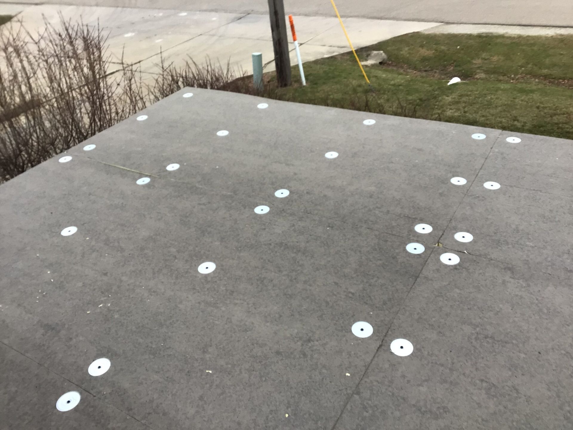 Gray concrete surface with many white washers attached.