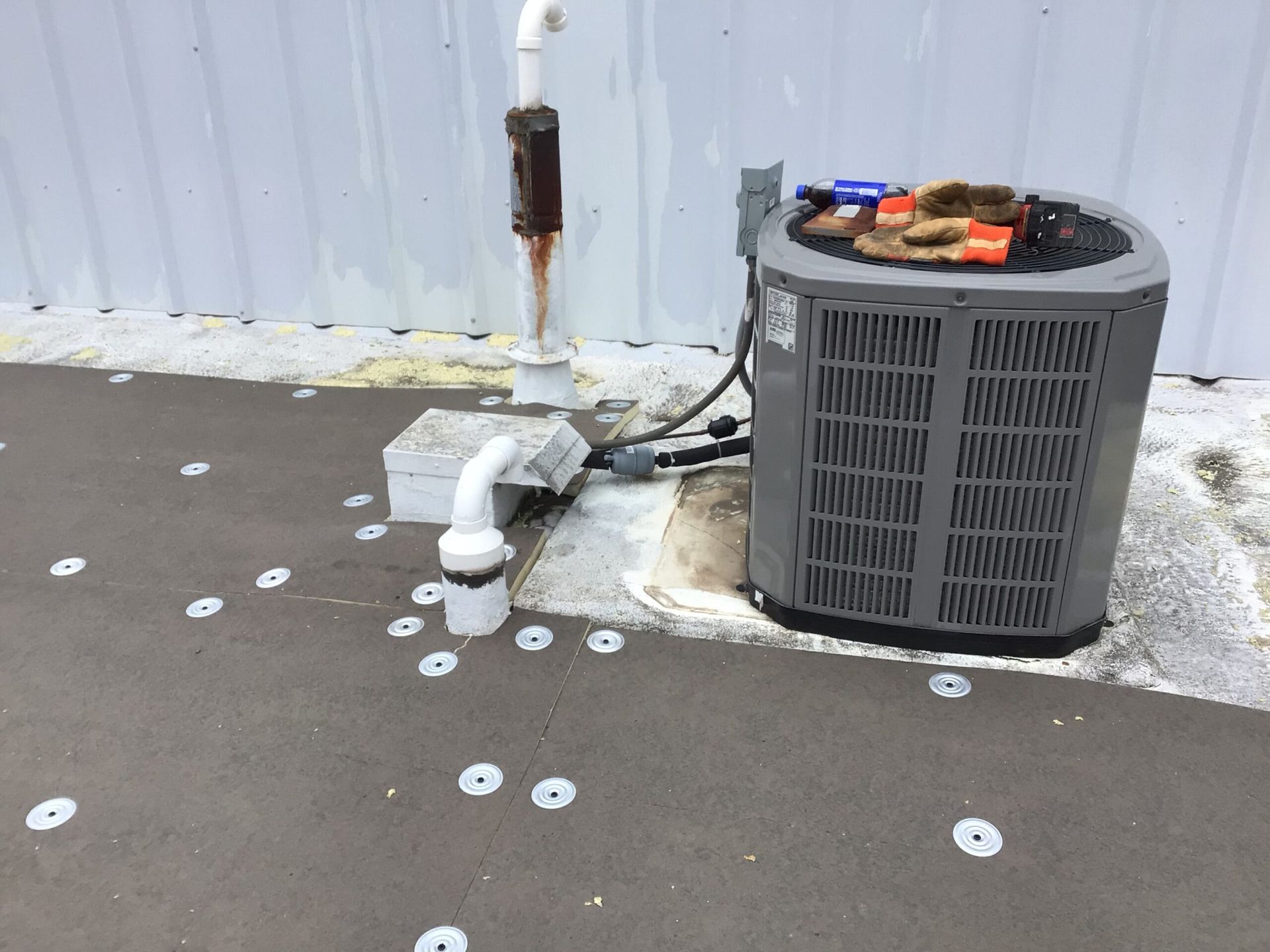 HVAC unit and piping on a flat roof. White fasteners and other components are visible.