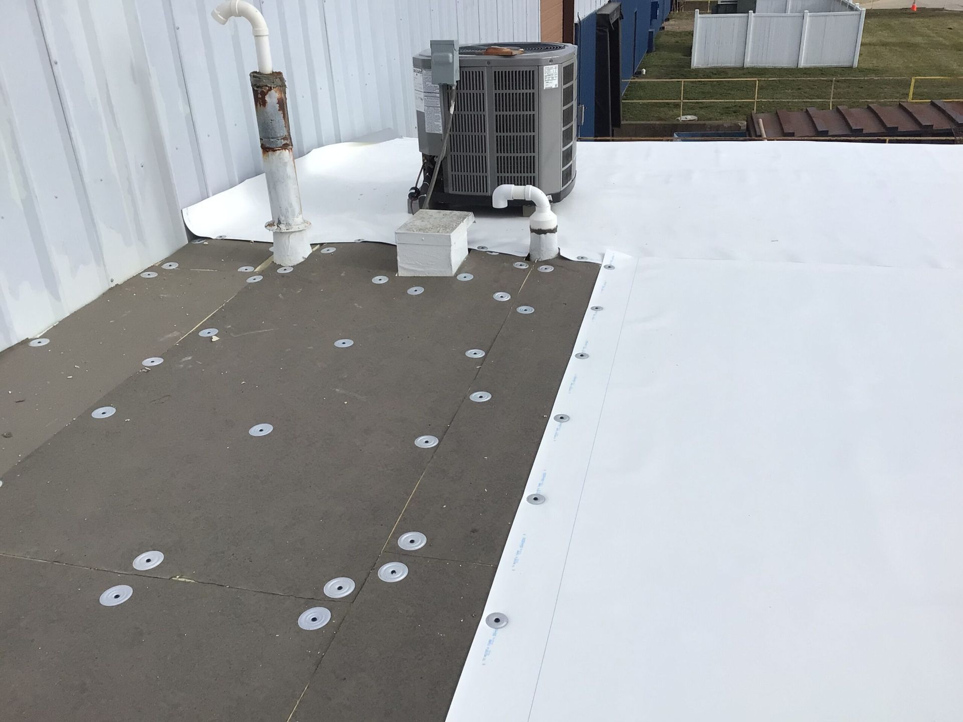 Flat commercial roof with HVAC unit and white membrane surface.