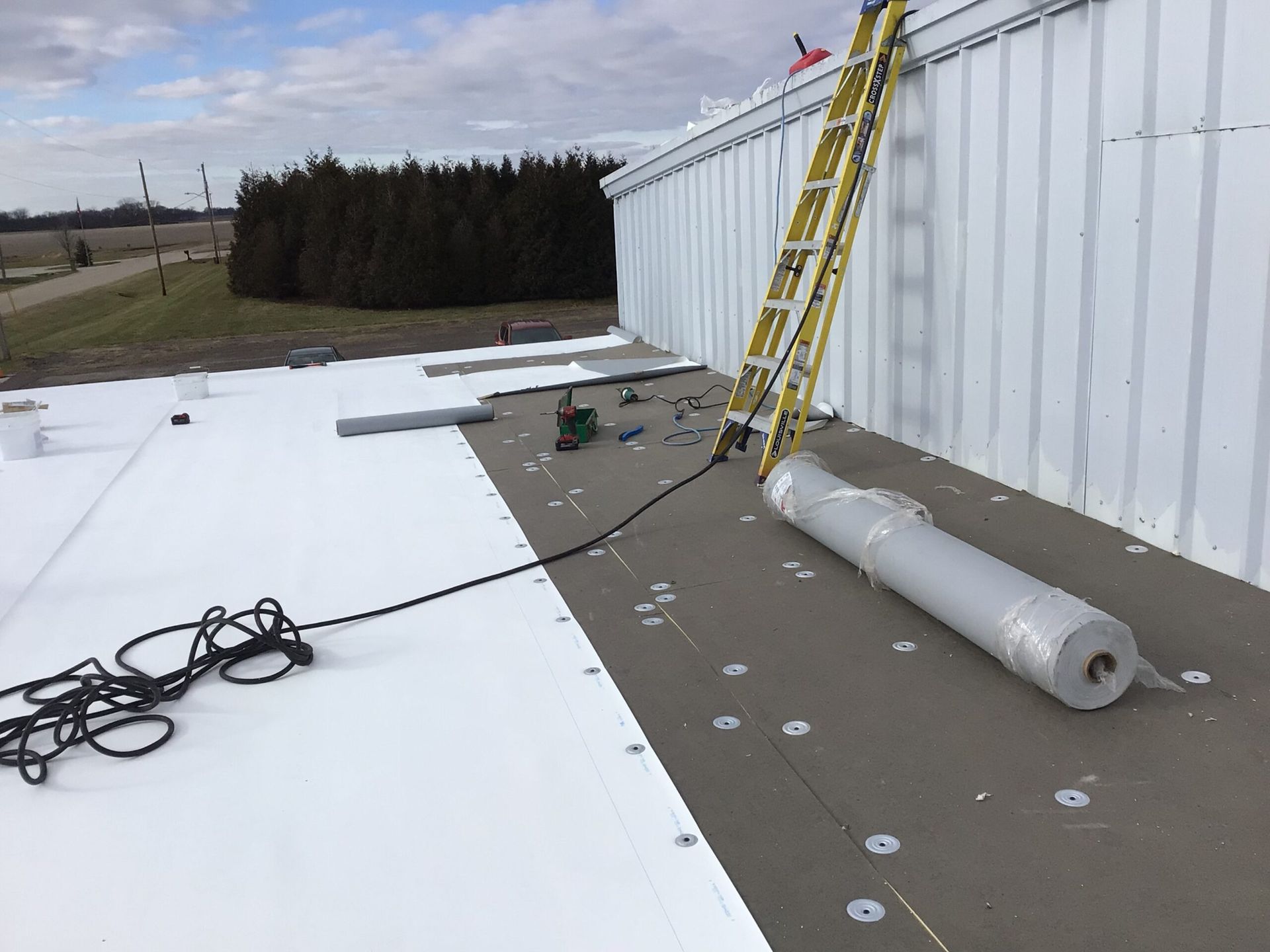 Flat roof with insulation and roofing materials. Ladder against the building.