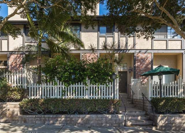 A house with a white picket fence and a green umbrella in front of it
