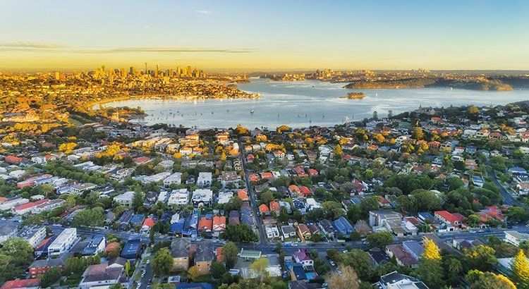 An aerial view of a residential area with a body of water in the background.