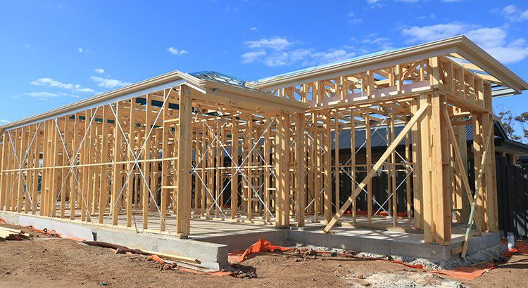 A house is being built with wooden beams and a blue sky in the background.