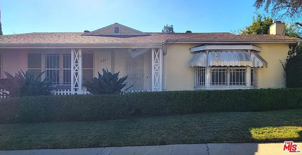 The front of a house with a porch and a hedge in front of it.