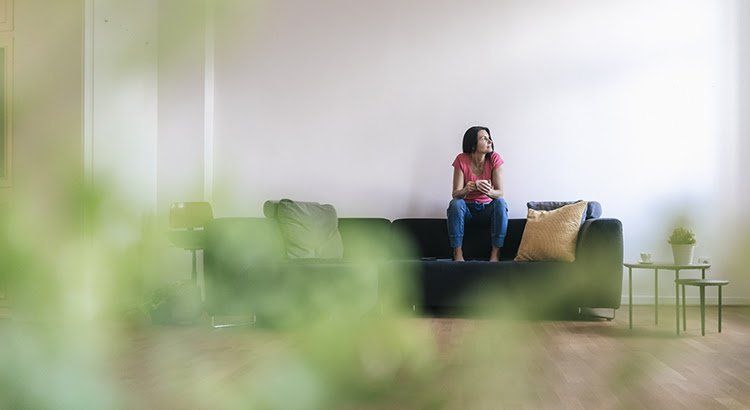 A woman is sitting on a couch in a living room.