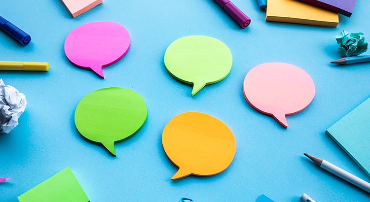 A bunch of colorful sticky notes in the shape of speech bubbles on a blue surface.