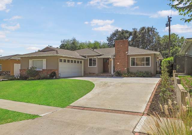 A house with a large driveway and a brick chimney is for sale.