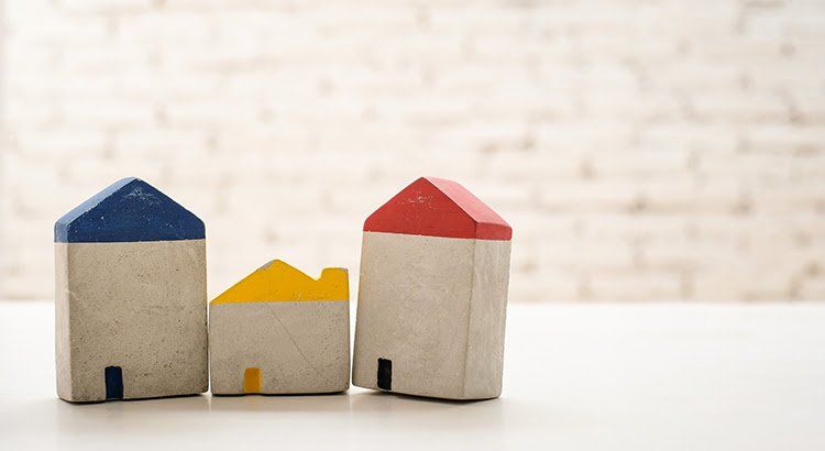 Three small wooden houses are lined up on a table.