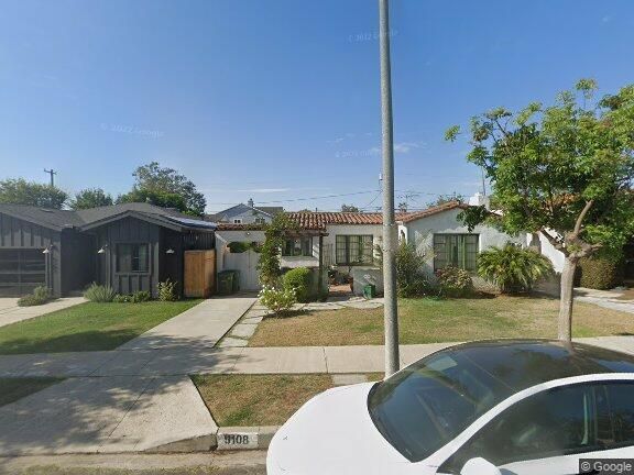 A white car is parked in front of a house