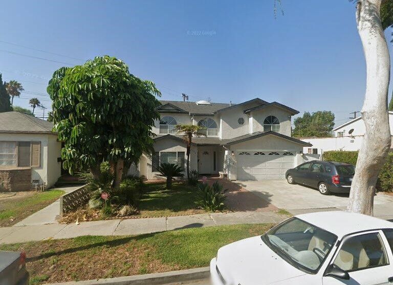 A white car is parked in front of a house