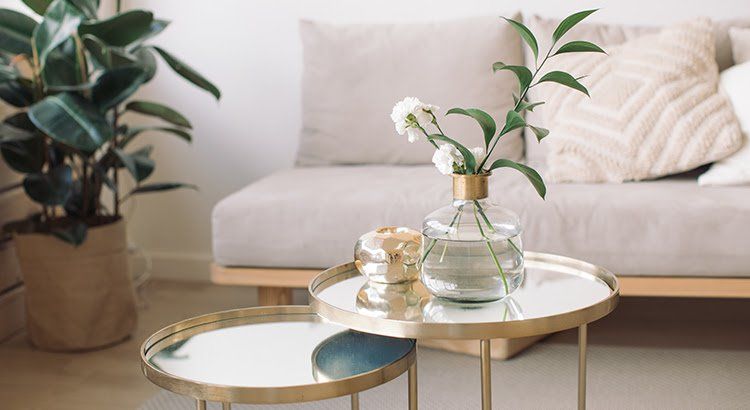 A living room with a couch and two tables with flowers on them.