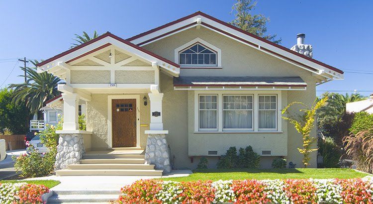 A house with a red roof and flowers in front of it.