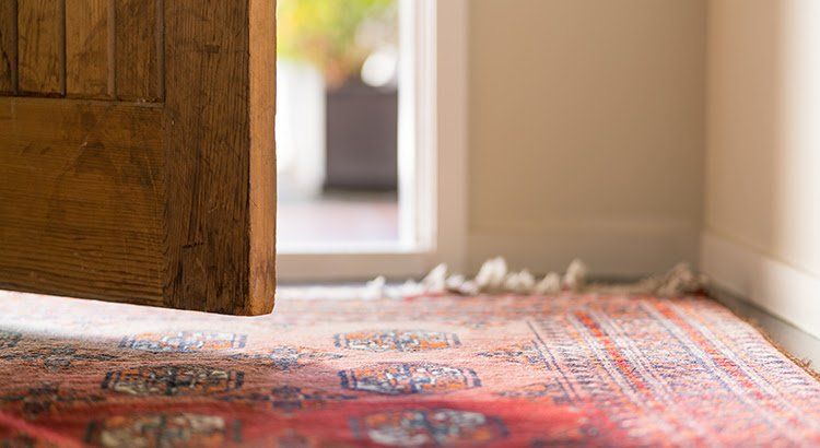 A red rug is on the floor in front of an open door.
