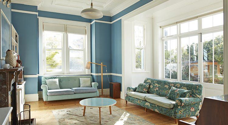 A living room with blue walls , two couches , a table , and a fireplace.