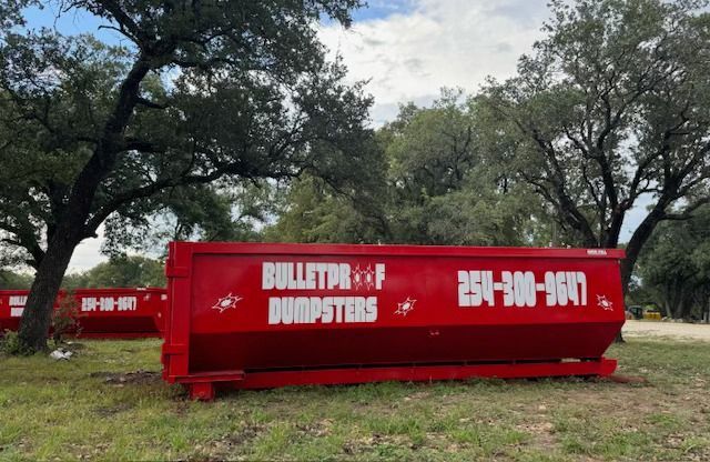A red dumpster is parked in front of a brick building.