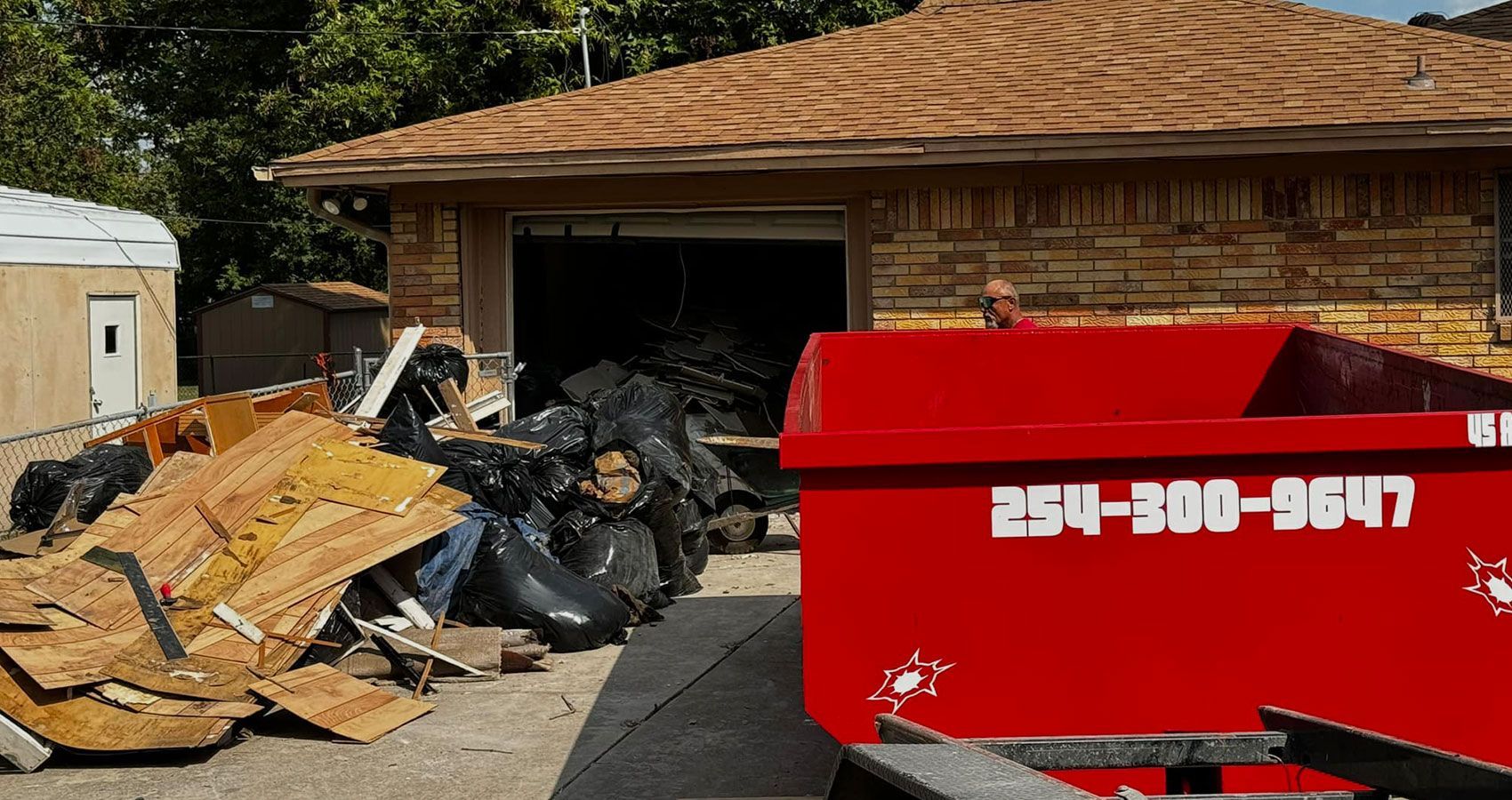 A red dumpster is parked in front of a house.