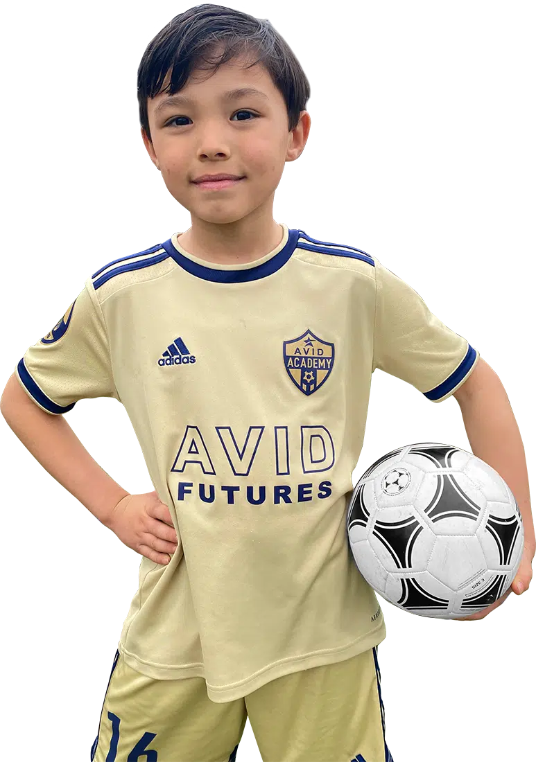 Child in a beige soccer uniform holding a black-and-white soccer ball, standing against a white background.
