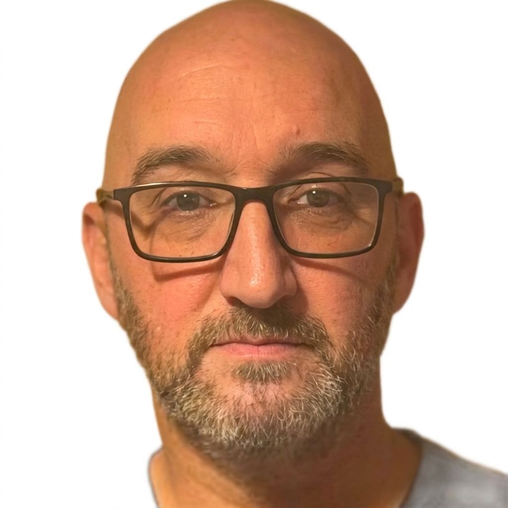 Close-up portrait of a bald man wearing glasses, with a gray beard, against a white background