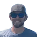 Smiling person wearing sunglasses and a cap against a bright white background