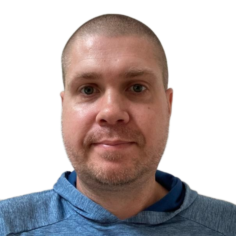 Close-up of a man with a shaved head wearing a blue shirt, facing forward against a white background