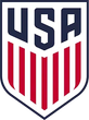 USA Soccer shield logo in navy, red, and white with vertical stripes and “USA” at top